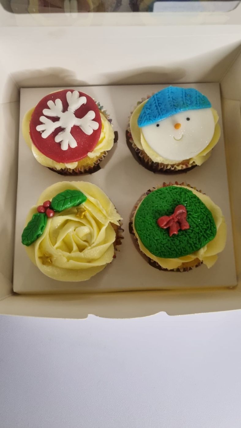 A box of festive cupcakes with fondant toppers
